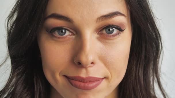 Close-up portret van jong aantrekkelijk brunette vrouw op witte achtergrond glimlacht en lacht naar de camera — Stockvideo