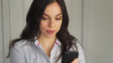 Genç bir kadın akıllı telefon kullanıyor ve dans ediyor. Oyuncu kız sosyal ağlarda akıllı bir telefonla flört ediyor.