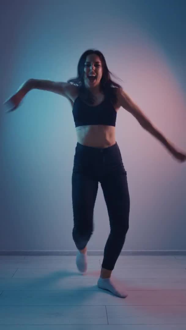 Vertikální video mladé tanečnice taneční výzva pro sociální síť v multi-barevné neonové osvětlovací místnosti — Stock video
