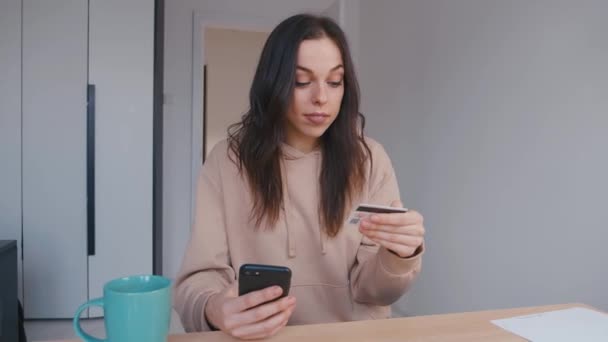 Lachende jonge vrouw online bankieren met behulp van smartphone online winkelen met creditcard thuis levensstijl. Eenvoudig betalen met behulp van digitale gadget. — Stockvideo