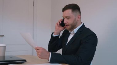 Pozitif girişimci işadamı ev ofisinde cep telefonundan duygusal olarak bahsediyor. Telefonla iş görüşmesi, iş akışı.