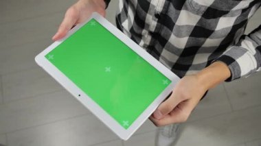 Adam ofiste duruyor ve elinde yeşil ekran krom anahtarıyla dijital tablet tutuyor.