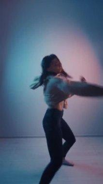 Çok renkli aydınlatma odasında sosyal ağ için dans eden genç kadın dansçısının dikey videosu