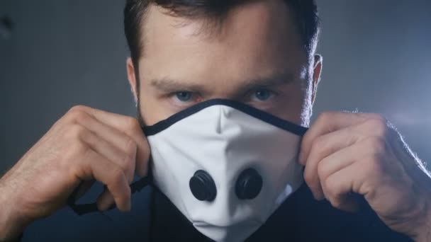 Close-up portrait of a businessman putting on a medical mask to protect against a pandemic virus — Stock Video