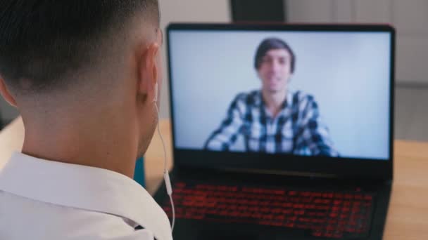 Молодой человек в наушниках смотрит онлайн веб-бинар с помощью ноутбука веб-конференц-связь дома . — стоковое видео