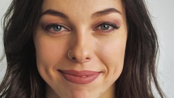 Close-up portrait of young attractive brunette woman on white background smiles and laughs to the camera — Stock Video