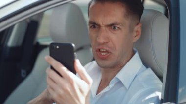 Kızgın Adam Sürücü, arabada otururken akıllı telefon kullanıyor. İşadamı akıllı telefon mesajını okuduğu için kızgın..