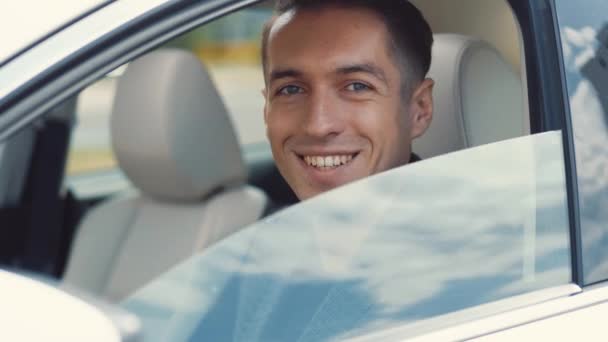 Портрет усміхненого чоловіка-бізнесмена, який сидить за кермом машини. Автомобільне вікно падає — стокове відео