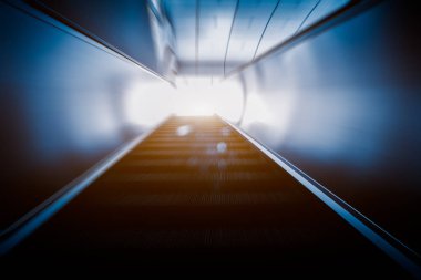 Mavi tonu bir metro istasyonunda yürüyen merdiven.