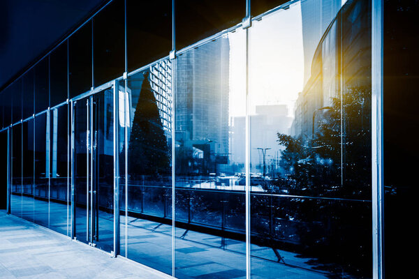 Modern glass building exterior with reflection,blue toned.