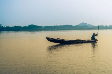 Yaşlı bir adam göl günbatımı sırasında Balık tutma görünümünü