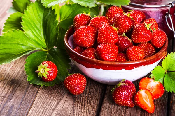 Erdbeere auf Holz Hintergrund. Erdbeere mit grünen Blättern — Stockfoto