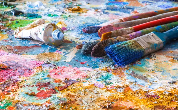 Oljefärger och målar borstar på en palett — Stockfoto
