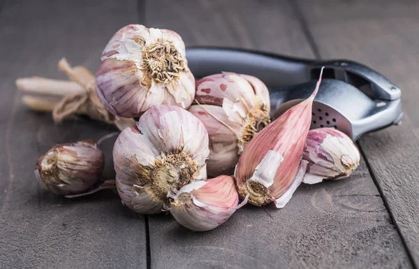 Organic garlic. Garlic press. Violet garlic.Wooden board.