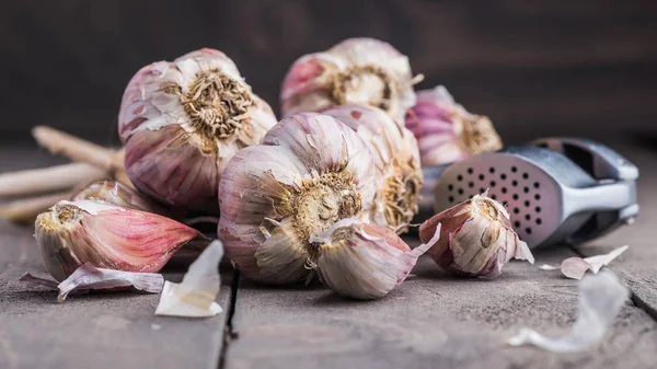 Organic garlic. Garlic press. Violet garlic.Wooden board.