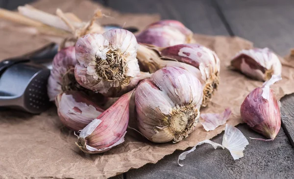 Organic garlic. Garlic press. Violet garlic.Wooden board.