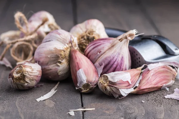 Organic garlic. Garlic press. Violet garlic.Wooden board.