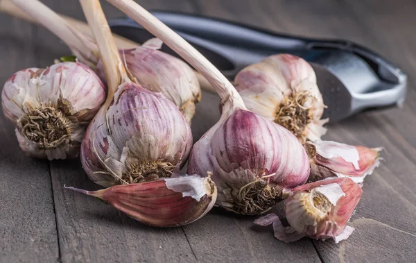 Organic garlic. Garlic press. Violet garlic.Wooden board.