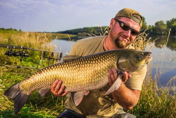 Happy angler with carp fishing trophy.Amur (grass carp).Fish tro