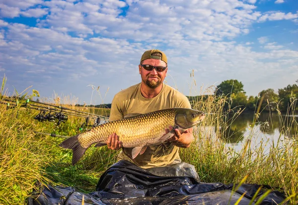 Happy angler med karp fiske trofé. Amur (gräskarp). Fisk tro — Stockfoto