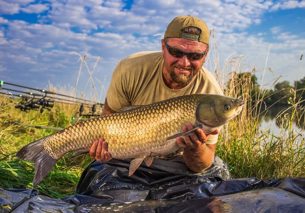 Happy angler med karp fiske trofé. Amur (gräskarp). Fisk tro — Stockfoto