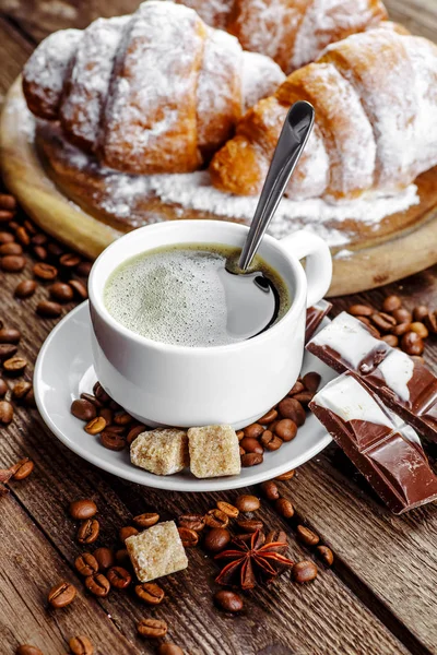 Desayuno con croissants, hojas, tabla de cortar y café negro — Foto de Stock