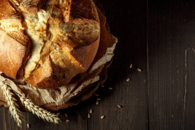 Koyu gri mutfak masasında taze pişmiş ekmek, üst manzara, fotokopi alanı. Tohumlu tam tahıllı çavdar ekmeği.