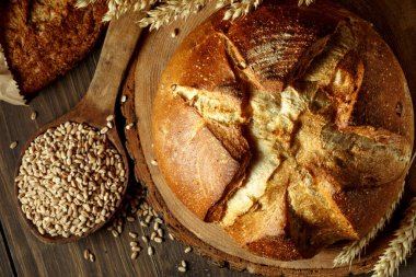 Koyu gri mutfak masasında taze pişmiş ekmek, üst manzara, fotokopi alanı. Tohumlu tam tahıllı çavdar ekmeği.