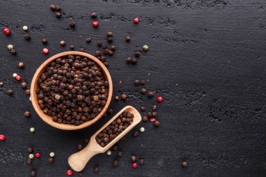 Bir biber seti. Farklı tip biber kolajı, siyah, beyaz, pembe ve tüm baharatlı biber, kurutulmuş kırmızı biber. Üst görünüm. Siyah bir arka planda. Metnin için boş yer.