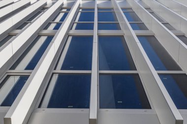 Cam pencereli güzel bir bina. İnşaat alanı mavi gökyüzüne karşı çalışıyor. Şehirde yeni bir bina..