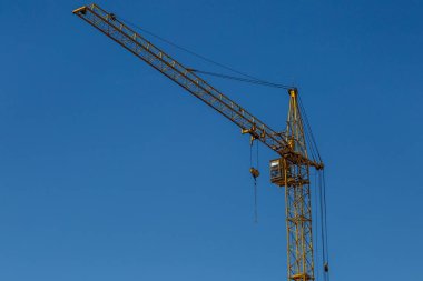 Yeni bir apartman bloğunda çalışma platformları sağlayan geniş kapsamlı yapı iskeleleri, inşaat halindeki uzun binalar, bir inşaat sahasındaki serbest kule vinci.