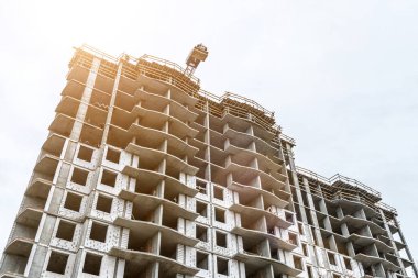 Yeni bir apartman bloğunda çalışma platformları sağlayan geniş kapsamlı yapı iskeleleri, inşaat halindeki uzun binalar, bir inşaat sahasındaki serbest kule vinci.