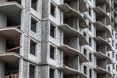 Yeni bir apartman bloğunda çalışma platformları sağlayan geniş kapsamlı yapı iskeleleri, inşaat halindeki uzun binalar, bir inşaat sahasındaki serbest kule vinci.