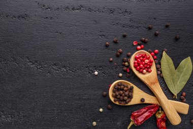 Bir biber seti. Farklı tip biber kolajı, siyah, beyaz, pembe ve tüm baharatlı biber, kurutulmuş kırmızı biber. Üst görünüm. Siyah bir arka planda. Metnin için boş yer.