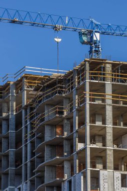 Yeni bir apartman bloğunda çalışma platformları sağlayan geniş kapsamlı yapı iskeleleri, inşaat halindeki uzun binalar, bir inşaat sahasındaki serbest kule vinci.