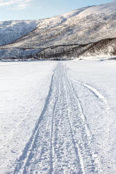 얼어붙은 강둑에서 작은 마을까지 뻗어 있는 눈 더미 길 — 스톡 사진