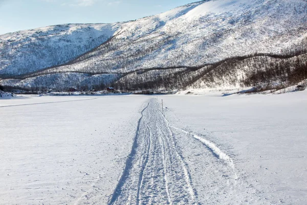 얼어붙은 강둑에서 작은 마을까지 뻗어 있는 눈 더미 길 — 스톡 사진