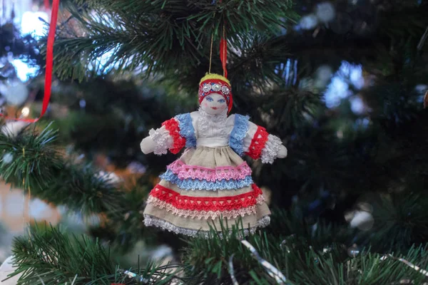 Handmade doll in folk costume decorates the New Year tree. Blurr