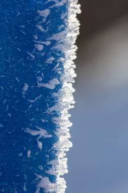 Ice crystals on a blue vertical surface. Macro. clipart