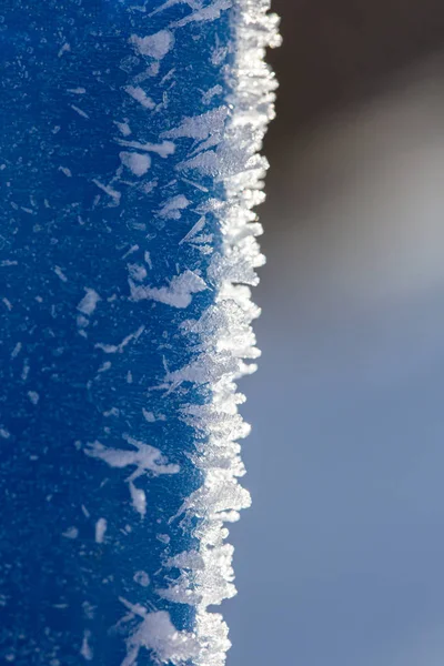 Cristales de hielo sobre una superficie vertical azul. Macro . Imagen De Stock