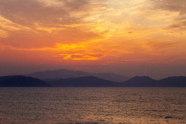 Güneşin dağdan batışının son ışınlarında kızgın bulutlar.