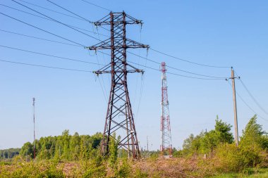 Birçok elektrik direği, teller, iletişim kuleleri, antenler bahar doğasının ve mavi gökyüzünün arka planına karşı..