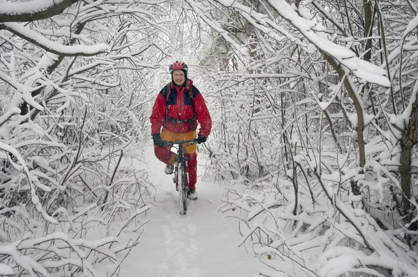 Um homem anda de bicicleta em queda de neve — Fotografia de Stock