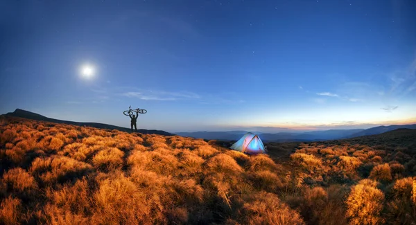 Cyclist at sunrise and tents