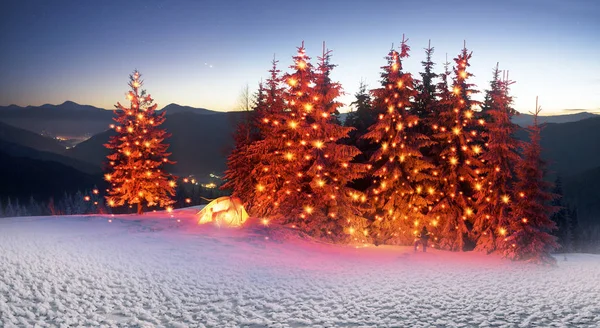 Snowy tent illuminated in mountains