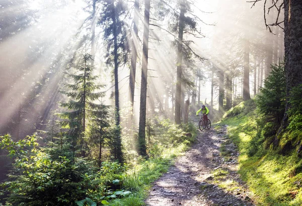 Homem de bicicleta em montanhas com raios de sol — Fotografia de Stock