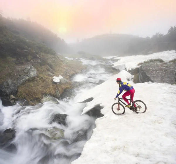 The bike rider on a mountain cliff — Stock Photo, Image