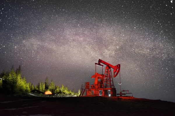 Classical technology of oil and gas extraction against background of eternal beauty of stars, Ukrainian Carpathians