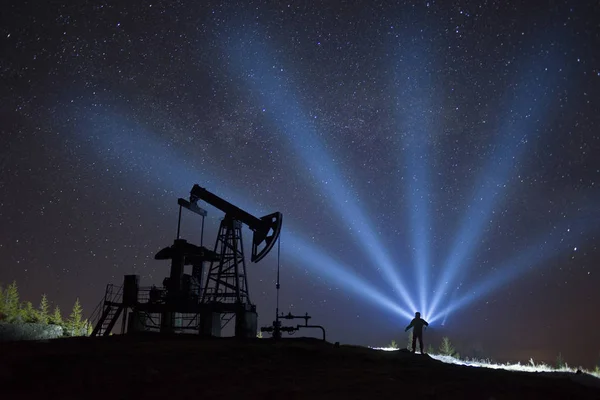 男性のシルエットを背景にレーザー光線と宇宙背景は ウクライナのカルパチア山脈を電動ポンプで石油と天然ガスの抽出の古典的な技術 — ストック写真