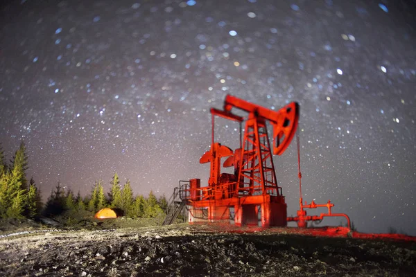 ウクライナのカルパチア山脈の宇宙の星の永遠の美しさの背景に電動ポンプで石油およびガス採掘の古典的な技術 — ストック写真